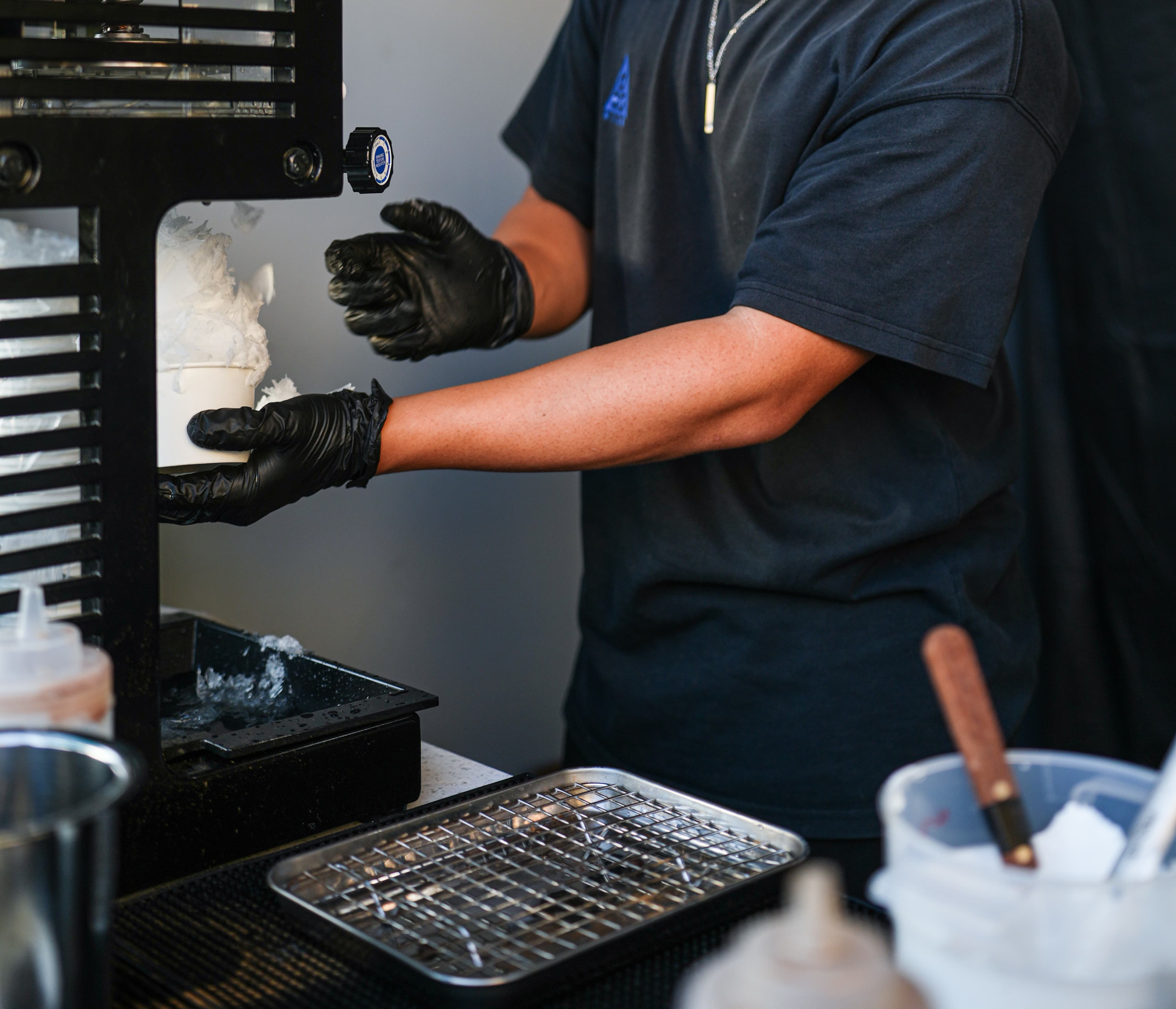 Hands operating a kakigori shaved ice machine